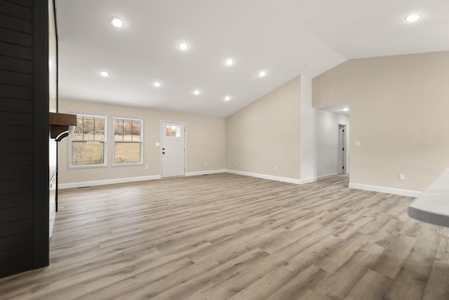 unfurnished living room with vaulted ceiling, light wood-style flooring, and baseboards