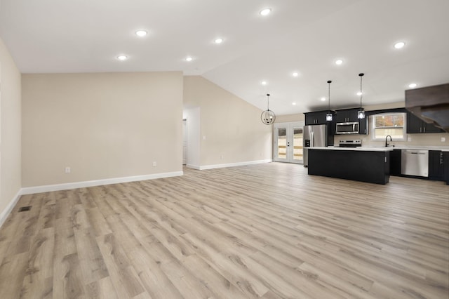 kitchen featuring lofted ceiling, stainless steel appliances, a kitchen island, open floor plan, and light countertops