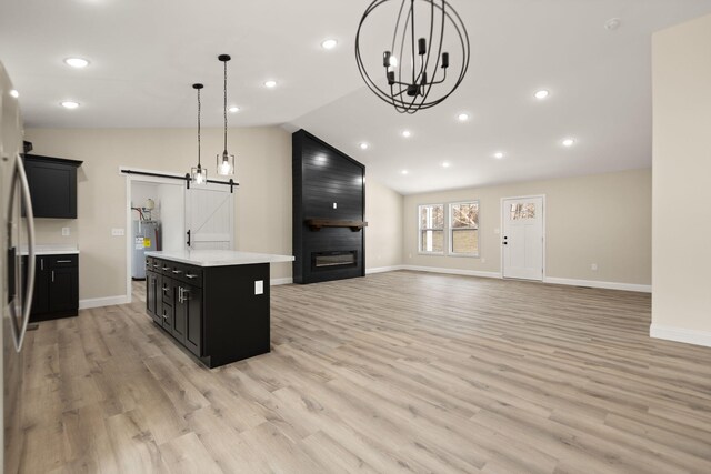 kitchen with lofted ceiling, light countertops, a barn door, electric water heater, and dark cabinetry