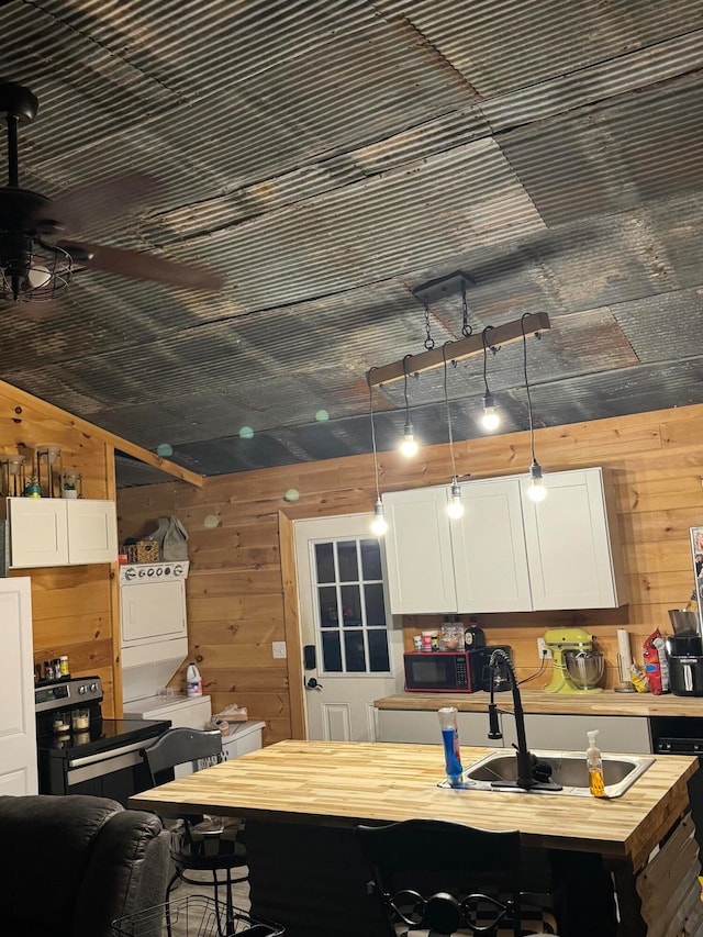 kitchen featuring sink, a kitchen island, wooden counters, pendant lighting, and white cabinets