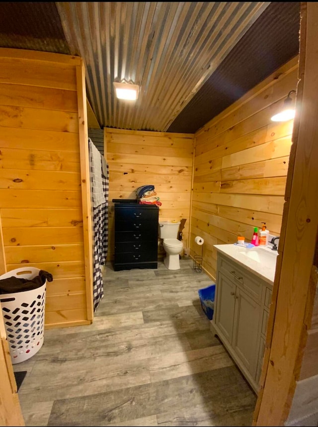 bathroom with vanity, toilet, wood walls, and hardwood / wood-style flooring