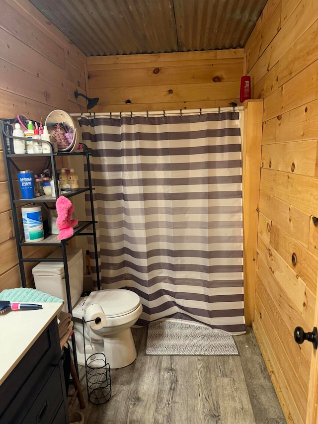 bathroom featuring wood-type flooring, toilet, vanity, wooden walls, and a shower with shower curtain