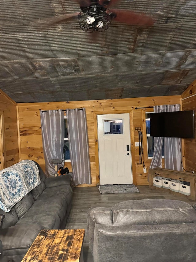 living room with lofted ceiling, ceiling fan, and wood walls