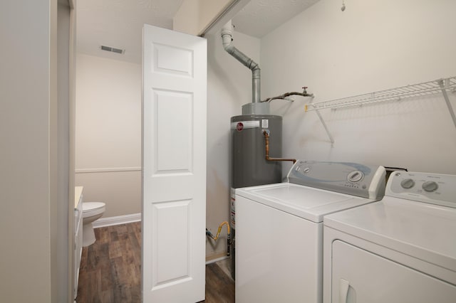 laundry area with water heater, dark hardwood / wood-style flooring, washer and dryer, and a textured ceiling