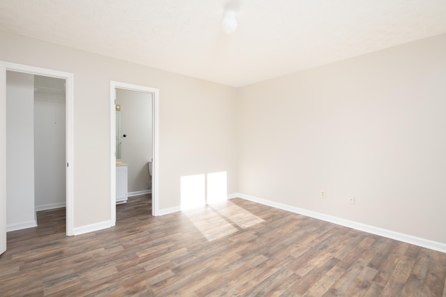 unfurnished bedroom with a closet, a spacious closet, and dark hardwood / wood-style floors