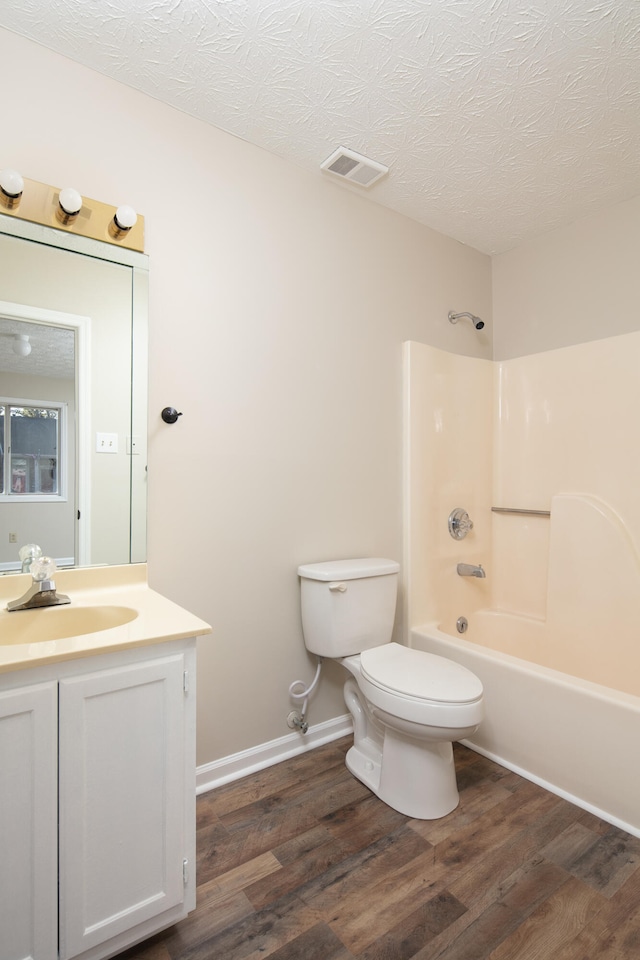 full bathroom featuring vanity, wood-type flooring, a textured ceiling, and shower / bathtub combination