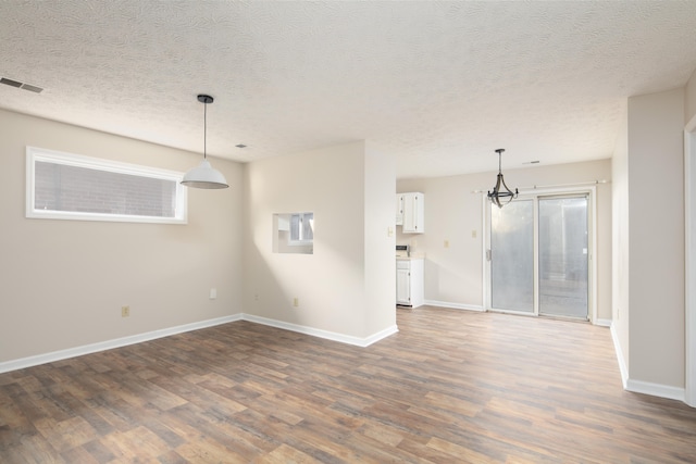 interior space featuring dark hardwood / wood-style flooring, a textured ceiling, and a notable chandelier