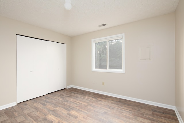 unfurnished bedroom featuring a closet, hardwood / wood-style floors, and a textured ceiling