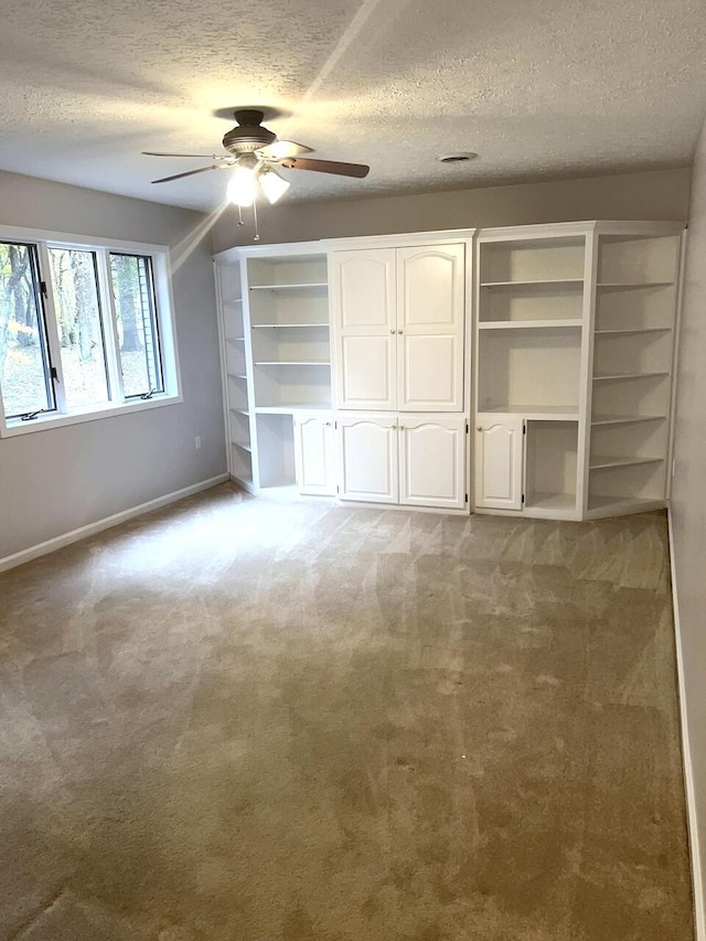 unfurnished bedroom featuring ceiling fan, light carpet, and a textured ceiling