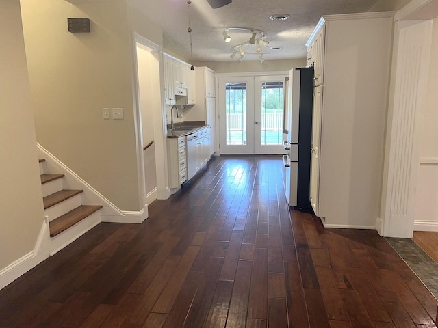 hall with french doors, rail lighting, sink, a textured ceiling, and dark hardwood / wood-style flooring