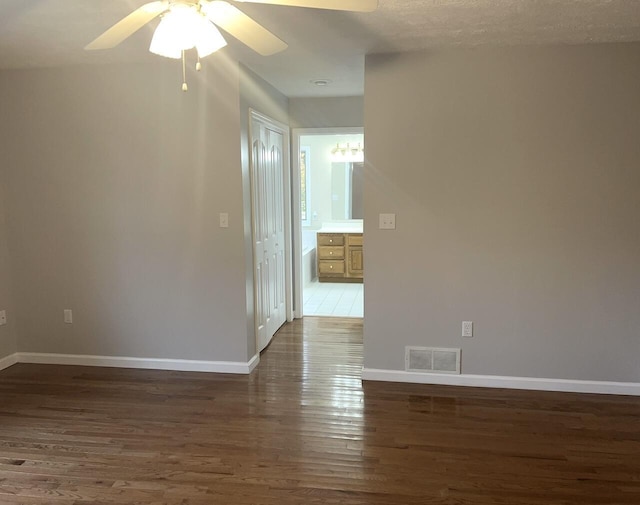 unfurnished room with ceiling fan, dark wood-type flooring, and a textured ceiling