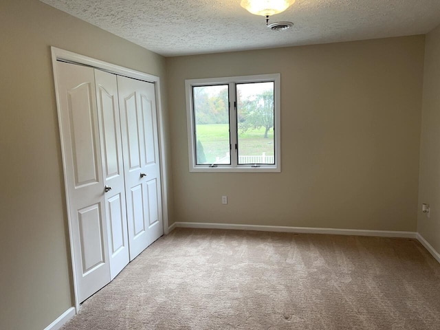 unfurnished bedroom featuring a closet, light colored carpet, and a textured ceiling