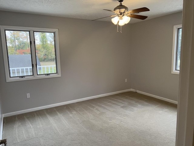 empty room with carpet flooring, ceiling fan, and a textured ceiling