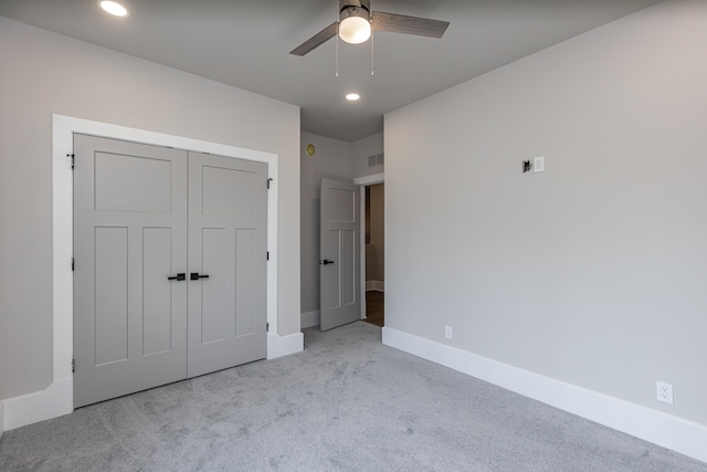 unfurnished bedroom featuring light carpet, a closet, and ceiling fan