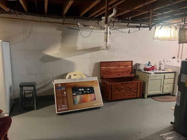 basement with washer / dryer, electric water heater, and white refrigerator