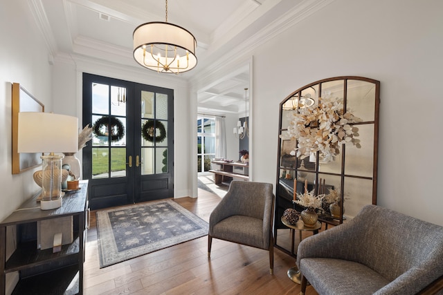 entrance foyer featuring a chandelier, french doors, wood-type flooring, and ornamental molding