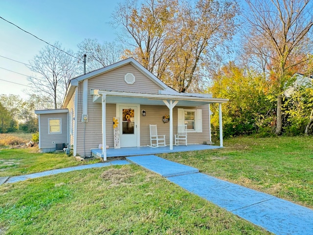 bungalow featuring a porch, a front lawn, and central AC unit