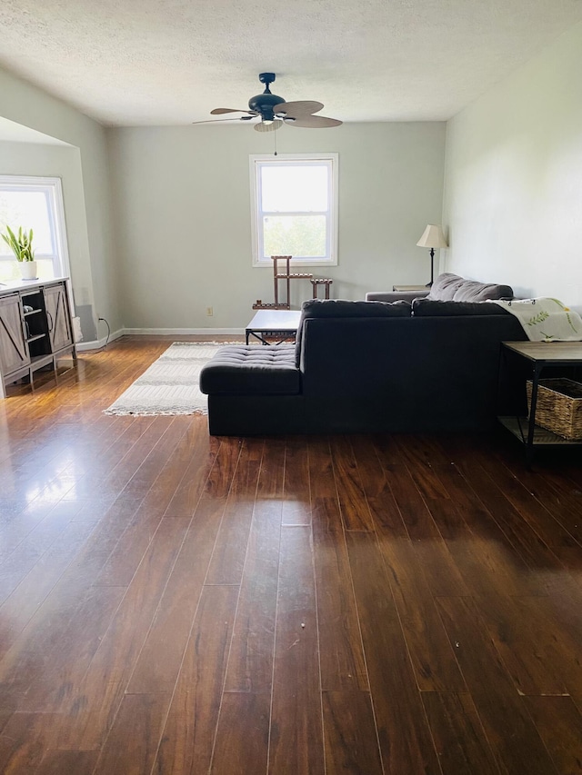 living room featuring ceiling fan, dark hardwood / wood-style flooring, and a textured ceiling