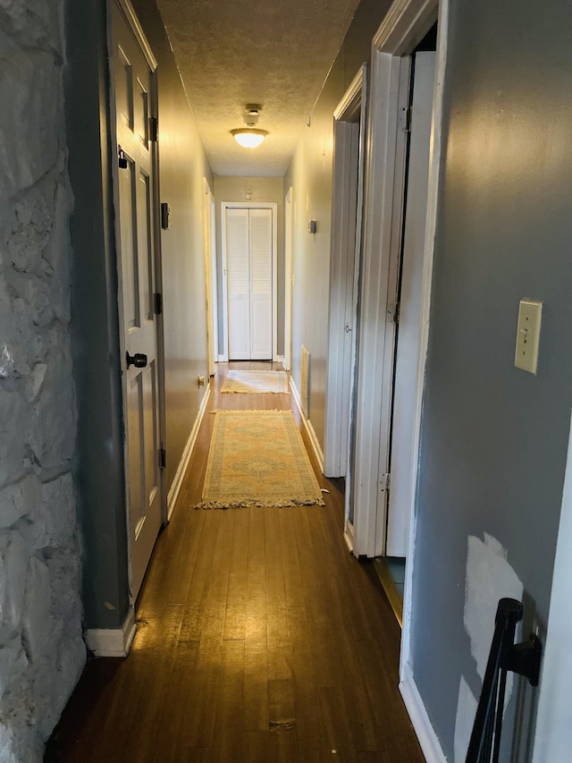 hallway with dark hardwood / wood-style floors and a textured ceiling