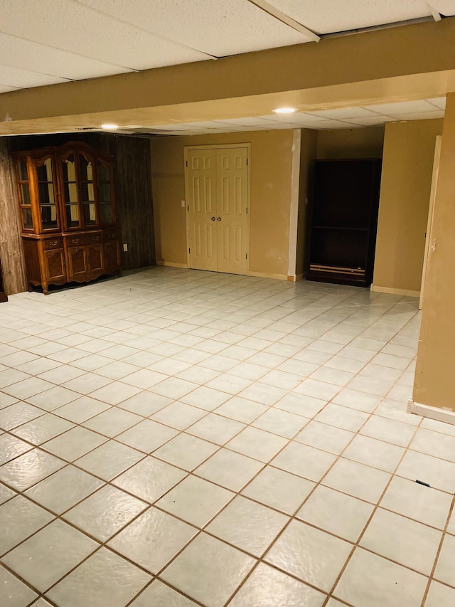 unfurnished room with a drop ceiling and light tile patterned floors