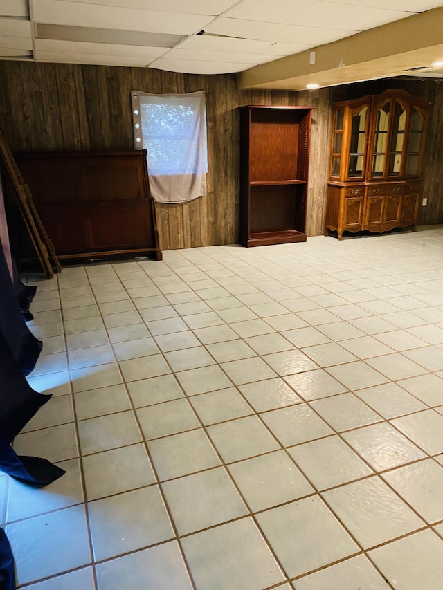 tiled spare room with wood walls and a drop ceiling