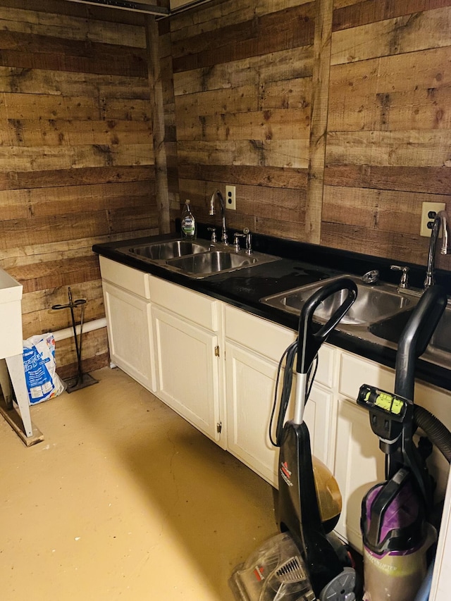 interior space featuring white cabinetry, wood walls, sink, and concrete flooring