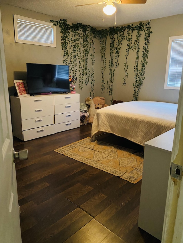 bedroom with a textured ceiling, dark hardwood / wood-style flooring, and ceiling fan