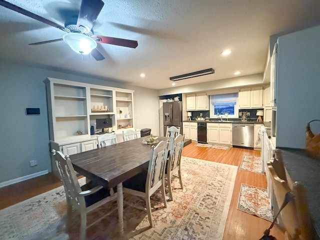 dining room with ceiling fan, light hardwood / wood-style flooring, a textured ceiling, and sink