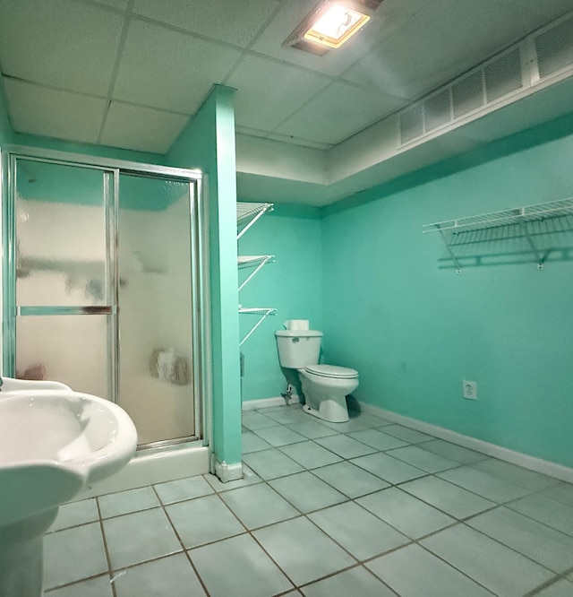 bathroom with tile patterned flooring, a drop ceiling, toilet, and walk in shower