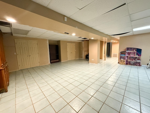 basement with a drop ceiling and light tile patterned flooring