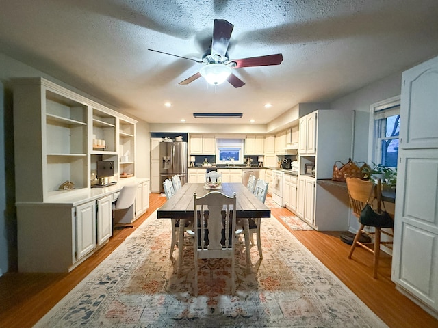 dining area featuring ceiling fan, a textured ceiling, and light wood-type flooring