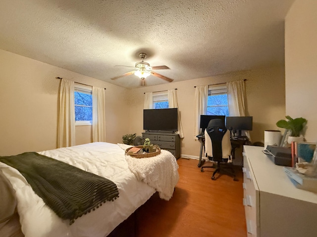 bedroom with ceiling fan, a textured ceiling, and light hardwood / wood-style flooring