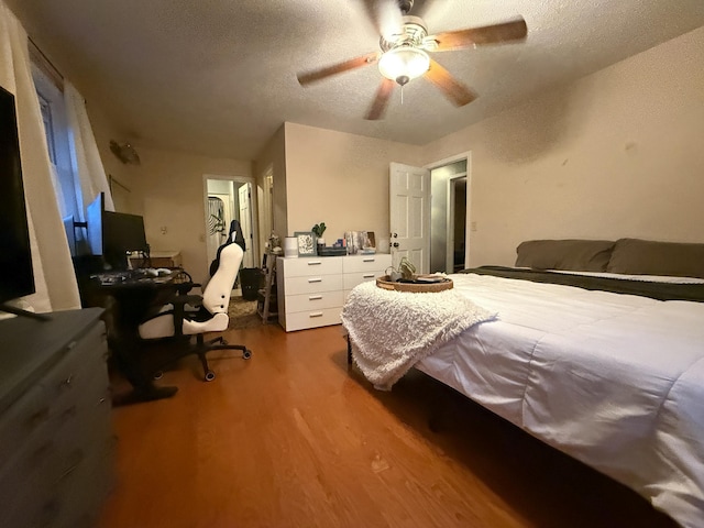 bedroom with hardwood / wood-style flooring, ceiling fan, and a textured ceiling