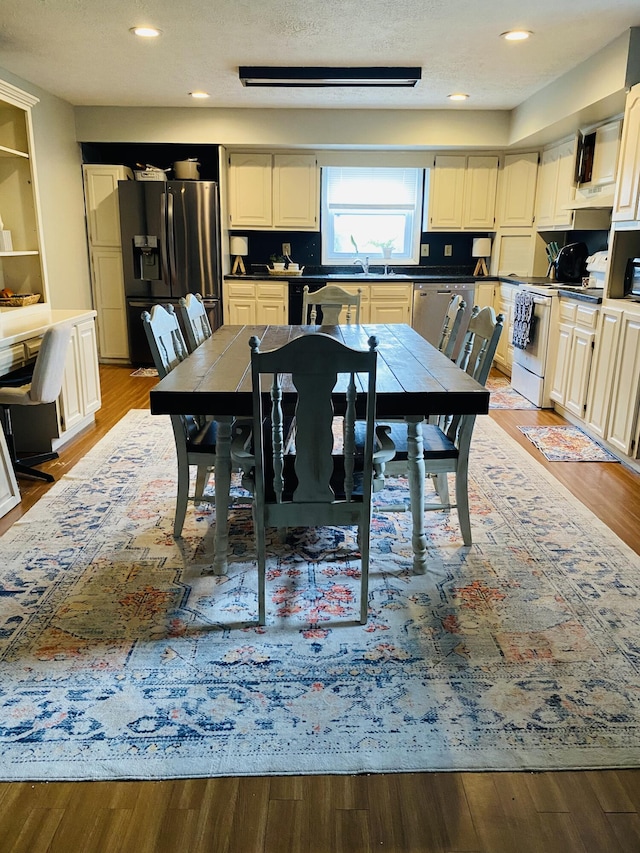 dining space featuring sink, a textured ceiling, and light wood-type flooring