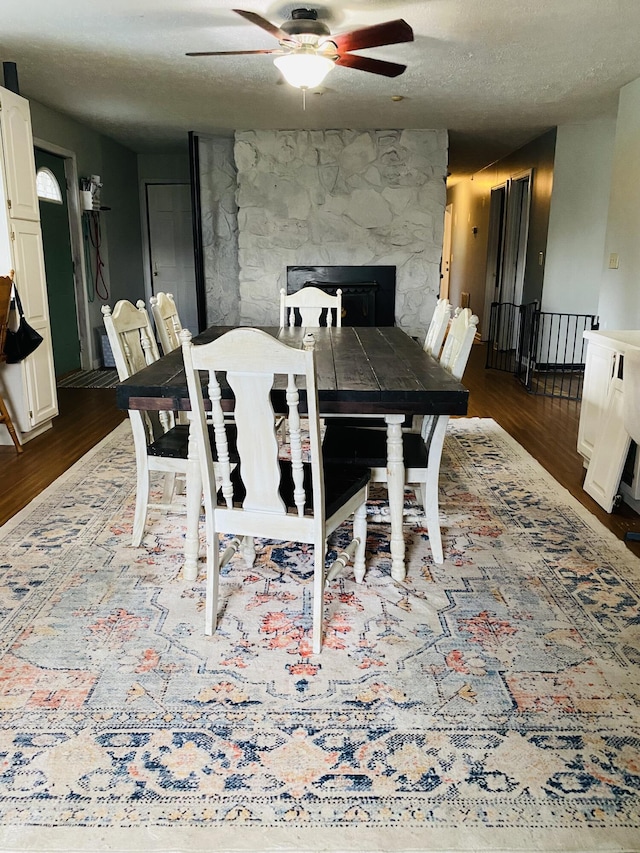 dining area with a textured ceiling, ceiling fan, and dark wood-type flooring