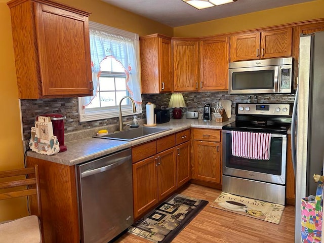 kitchen featuring backsplash, sink, stainless steel appliances, and light hardwood / wood-style floors