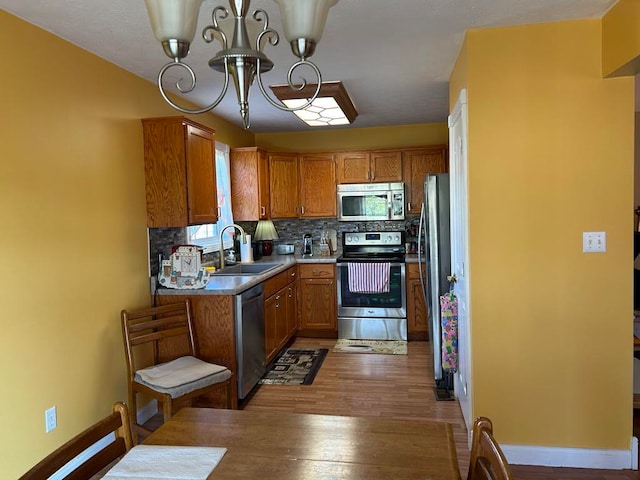 kitchen featuring tasteful backsplash, hardwood / wood-style flooring, a chandelier, sink, and stainless steel appliances