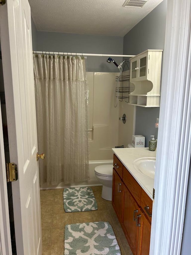 full bathroom with a textured ceiling, toilet, vanity, shower / tub combo with curtain, and tile patterned floors