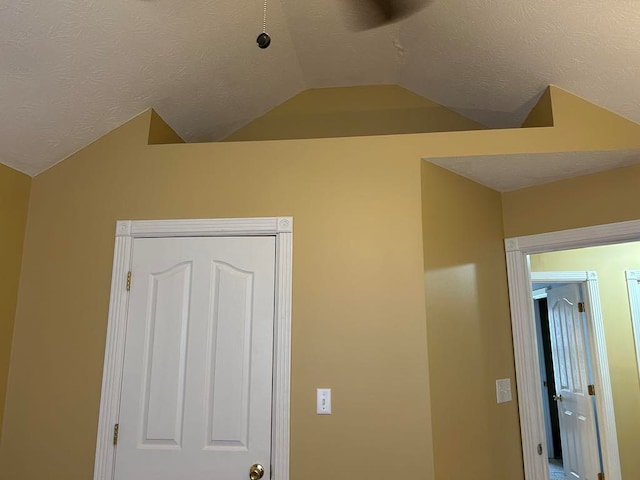 unfurnished bedroom featuring a closet, a textured ceiling, and lofted ceiling