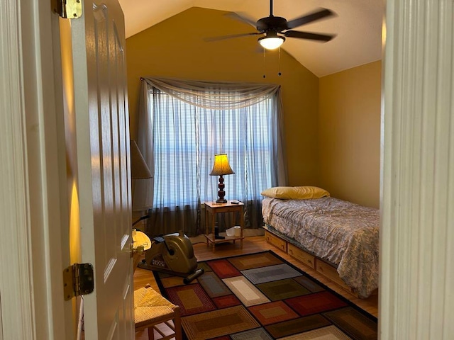 bedroom featuring ceiling fan, hardwood / wood-style flooring, and vaulted ceiling