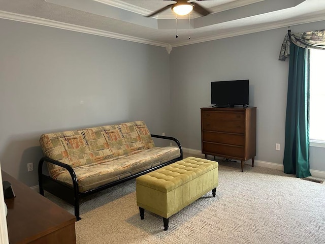 living area featuring crown molding, light carpet, a tray ceiling, and ceiling fan