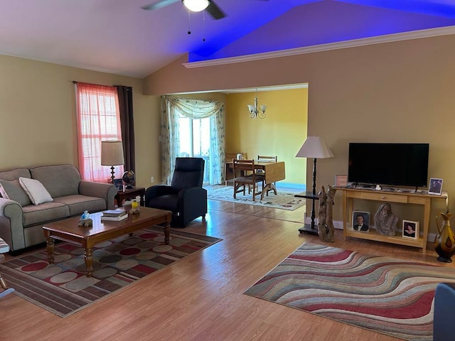 living room featuring lofted ceiling, ornamental molding, wood-type flooring, and ceiling fan with notable chandelier