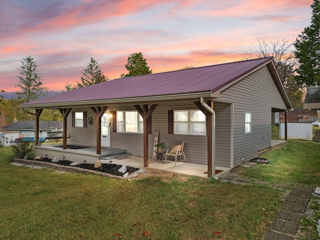 back house at dusk featuring a storage shed and a lawn