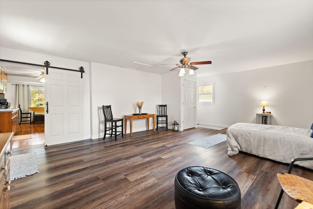 bedroom with dark wood-type flooring, a barn door, and ceiling fan