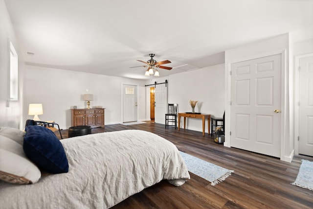 bedroom featuring dark wood-type flooring, a barn door, and ceiling fan