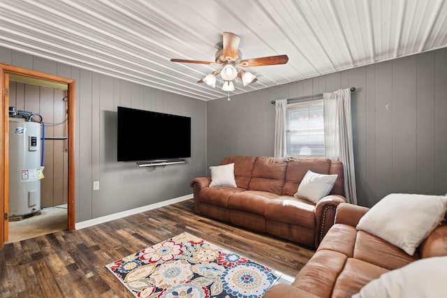 living room with ceiling fan, wood walls, electric water heater, and dark hardwood / wood-style floors