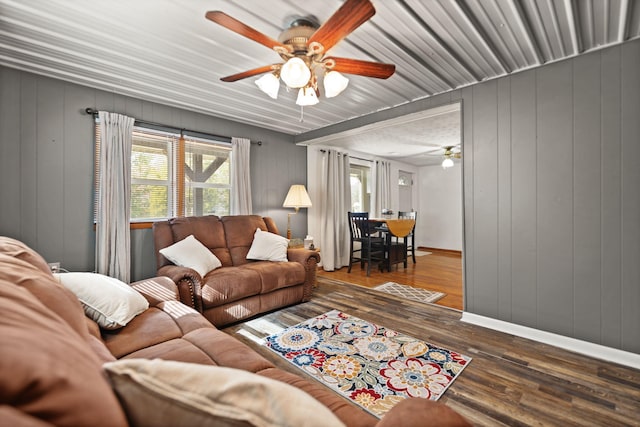 living room with wood walls, dark hardwood / wood-style floors, and ceiling fan