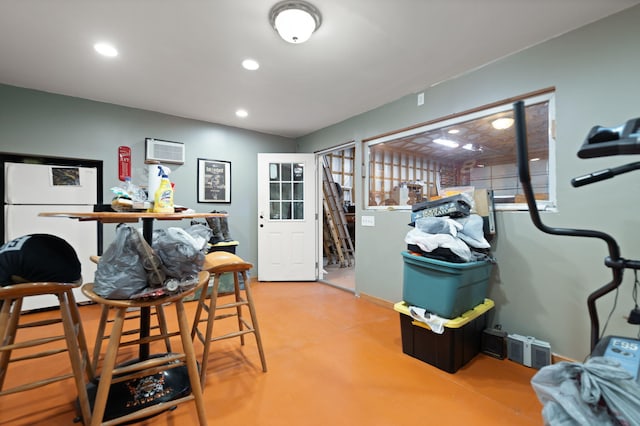 interior space with a wall unit AC and white refrigerator