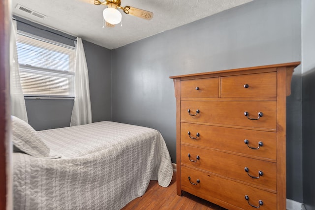 bedroom with ceiling fan, a textured ceiling, and light wood-type flooring