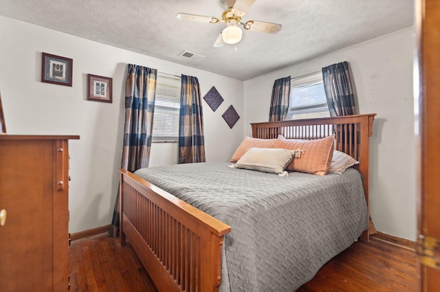 bedroom with ceiling fan, a textured ceiling, and dark hardwood / wood-style floors